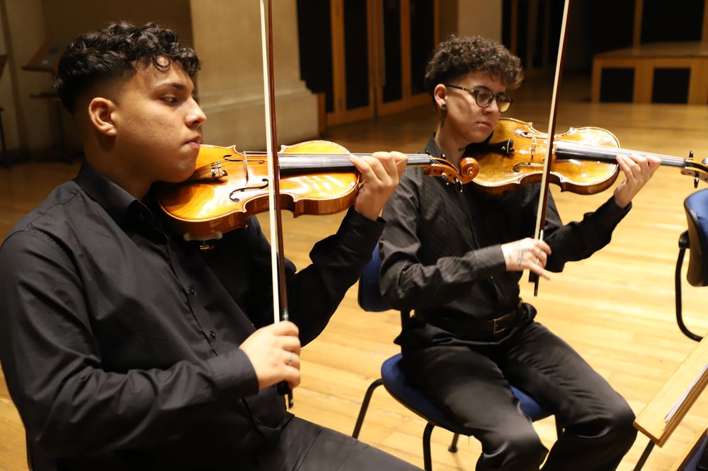 Violinistas da USP Filarmônica em close durante concerto